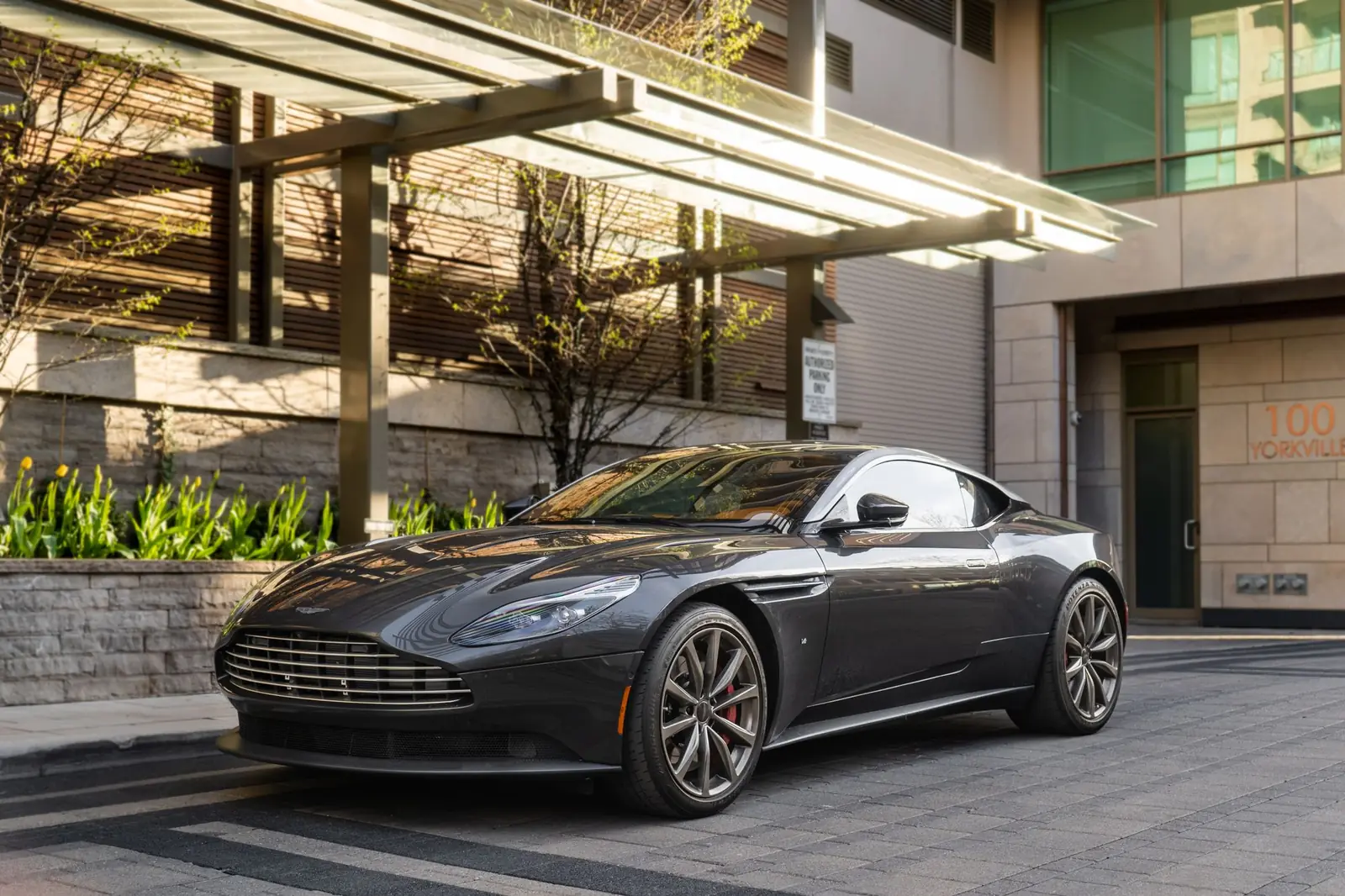 Aston Martin DB11 gris oscuro aparcado frente a un edificio