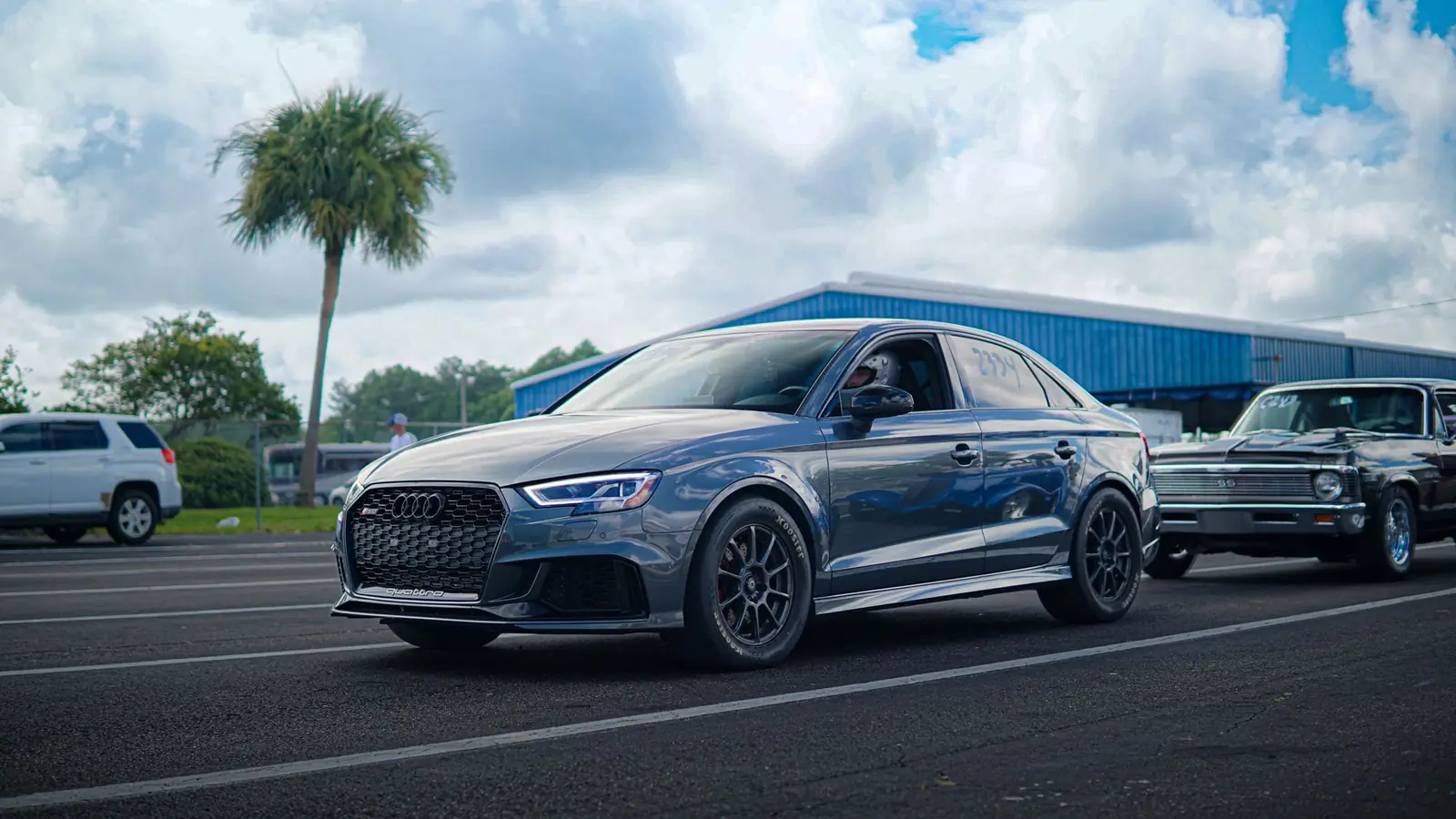 Audi RS 3 plateado aparcado bajo un cielo nublado