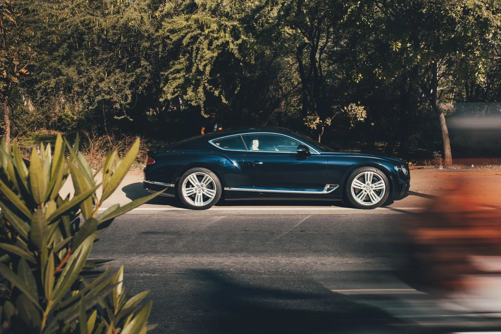 Bentley Continental GT azul oscuro en una calle arbolada