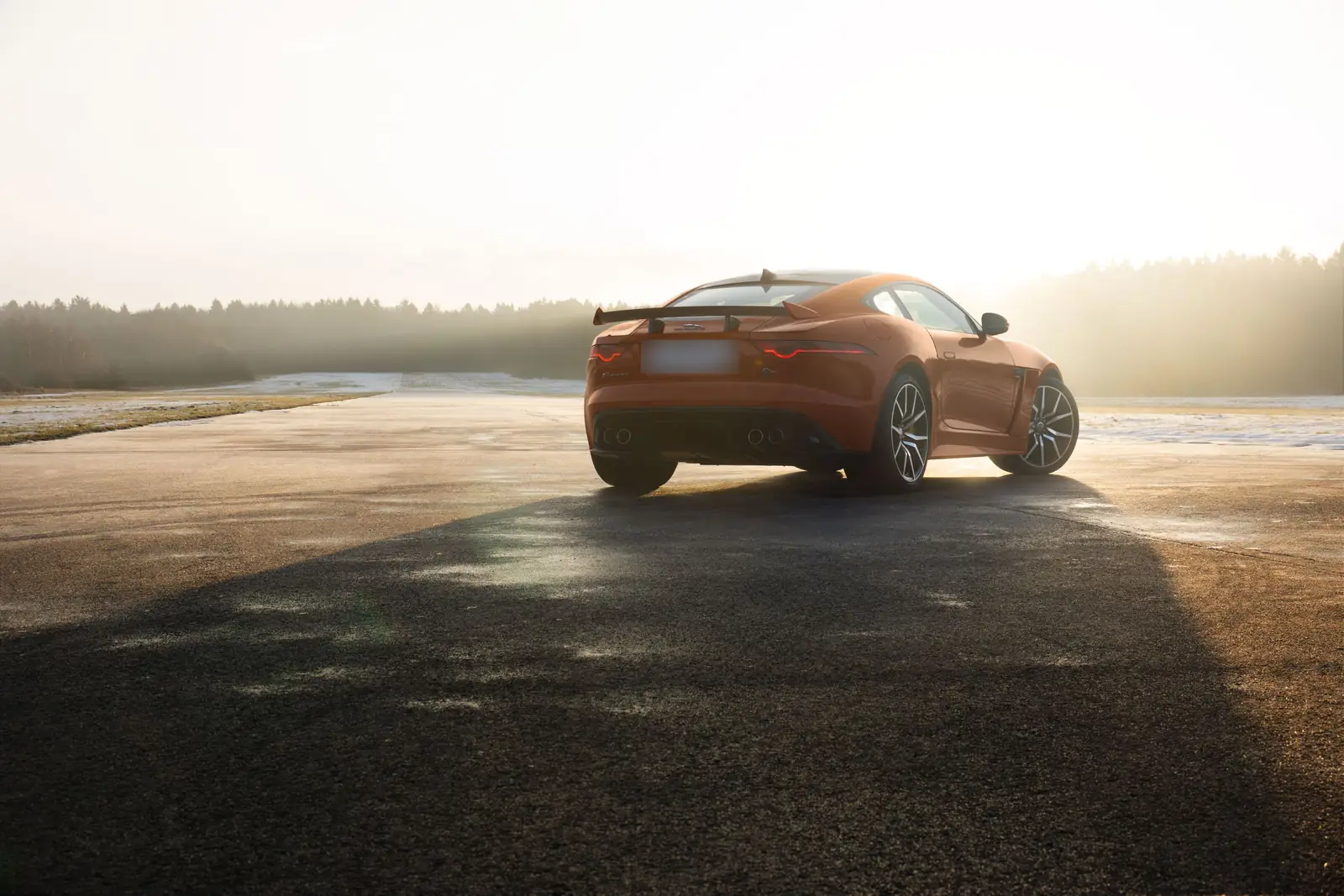 Jaguar F-Type naranja aparcado en una carretera al atardecer