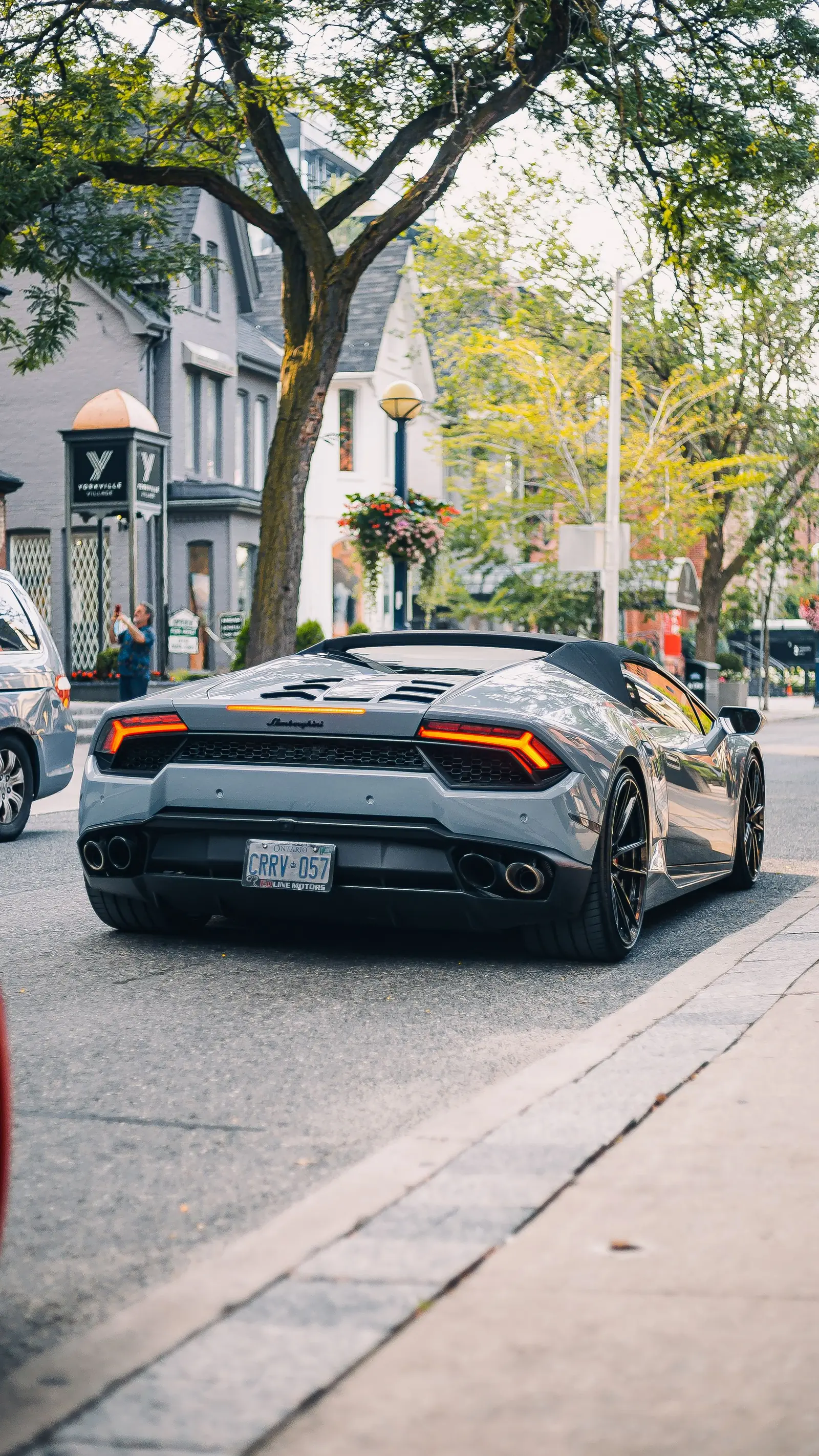Lamborghini Huracán gris circulando por una calle arbolada