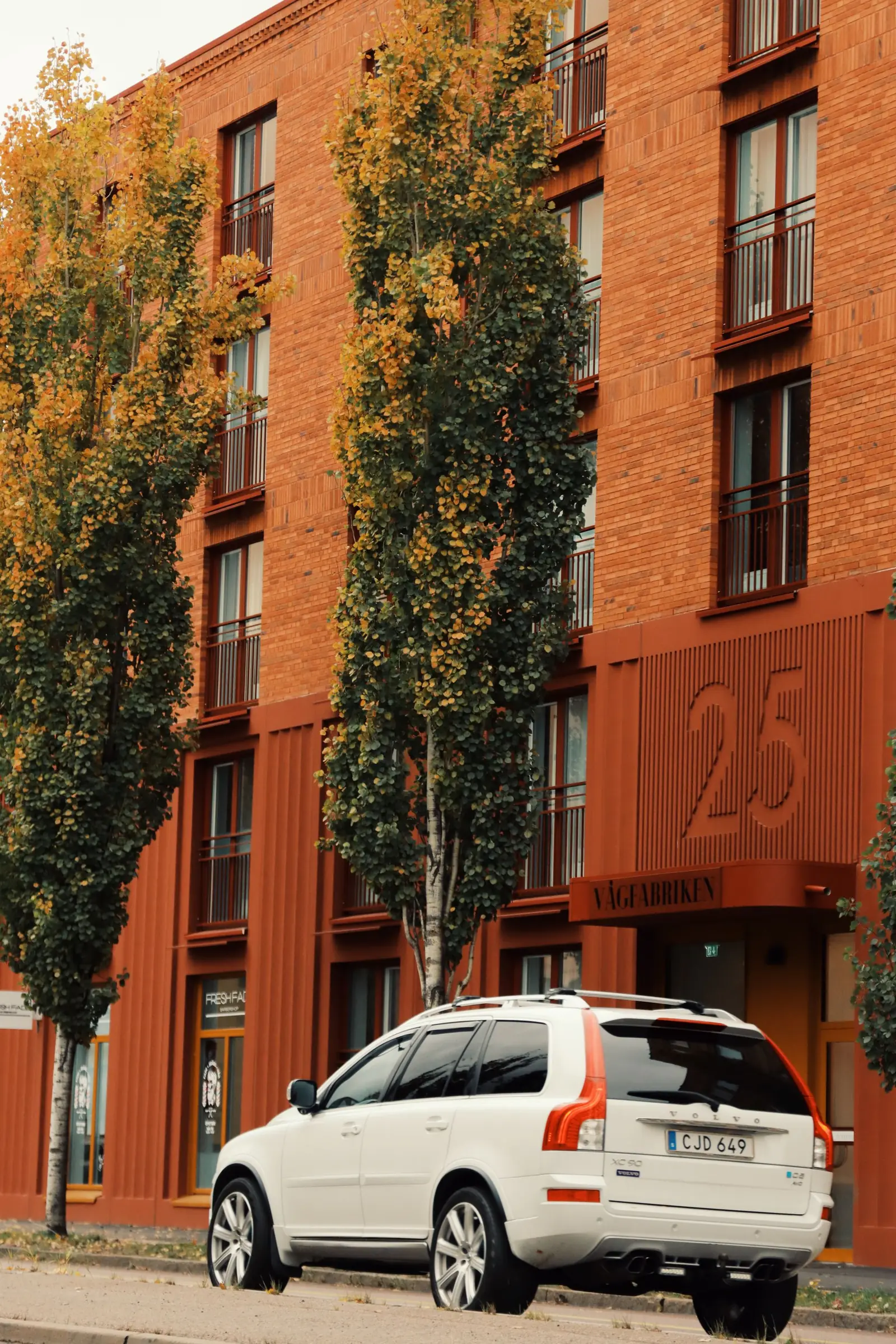 Volvo XC90 blanco de primera generación junto a un edificio residencial