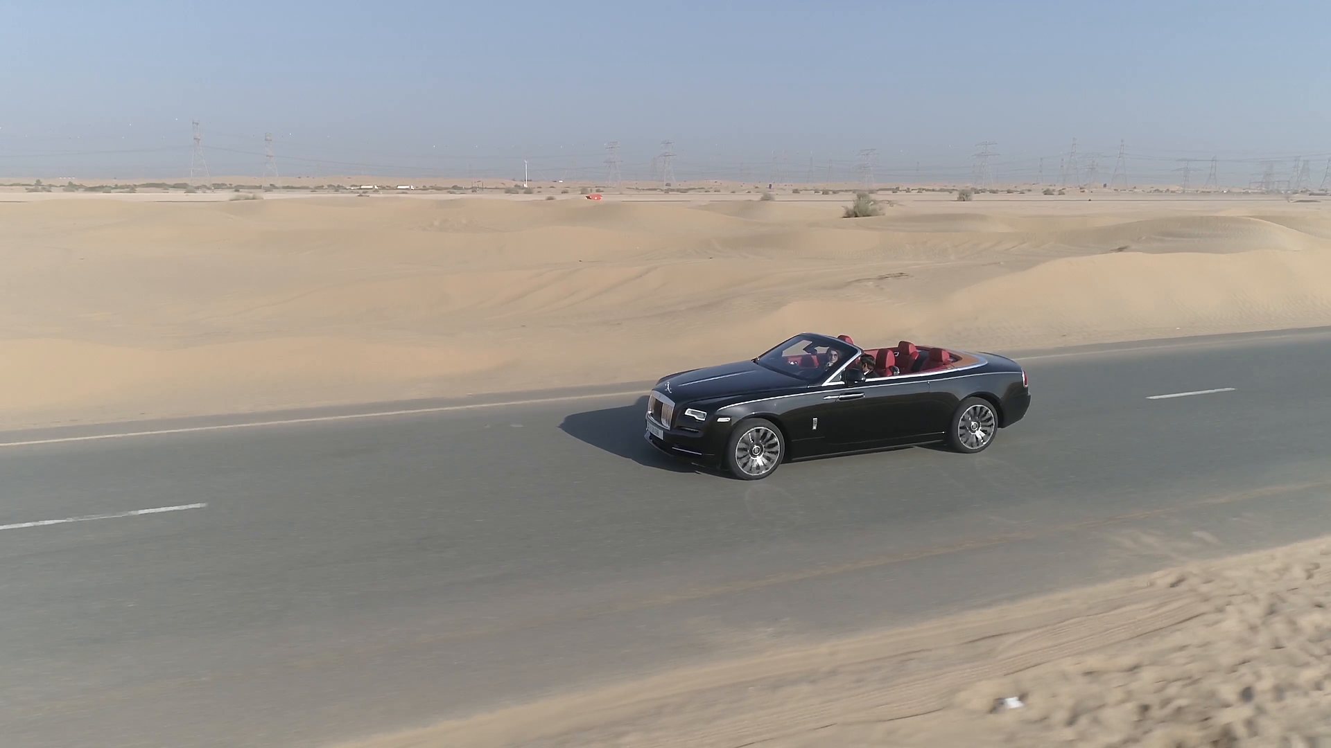 Rolls-Royce descapotable negro circulando por una carretera del desierto